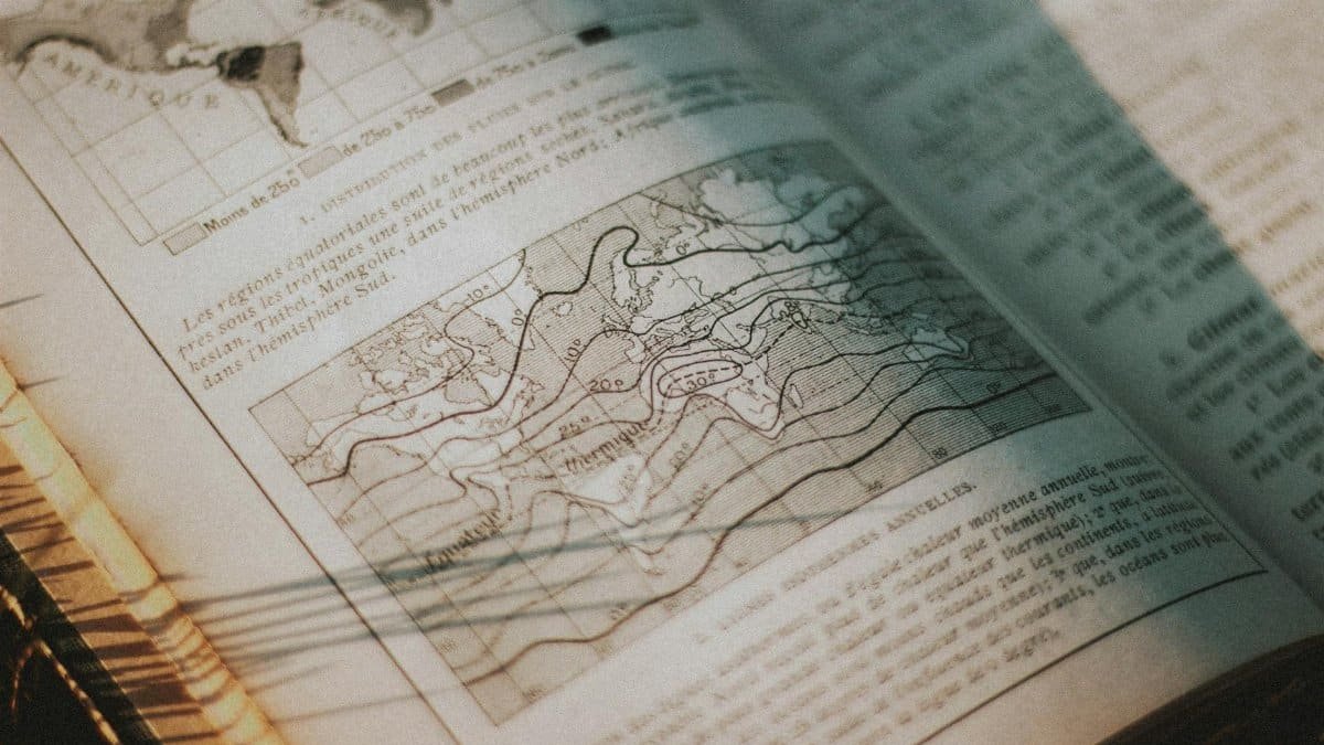 Open vintage book showing a detailed map and text under soft sunlight.