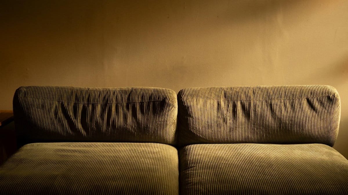 A plush corduroy sofa bathed in warm ambient lighting, perfect for cozy interiors.