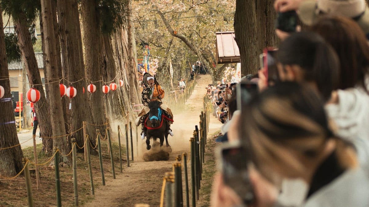A skilled samurai performs yabusame, traditional horseback archery, amid a vibrant festival in Japan.