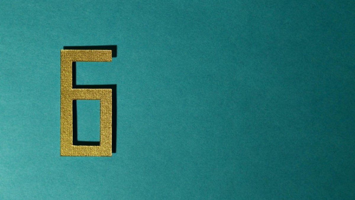 A golden number six on a teal background, perfect for decorative purposes.