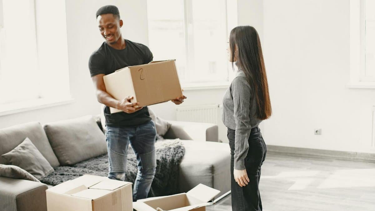 Happy couple carrying boxes into their new home, symbolizing a fresh start indoors with lots of natural light.