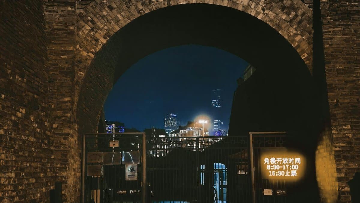 Night view of a historic gate leading to Beijing's vibrant skyline, captured beautifully in the dark.