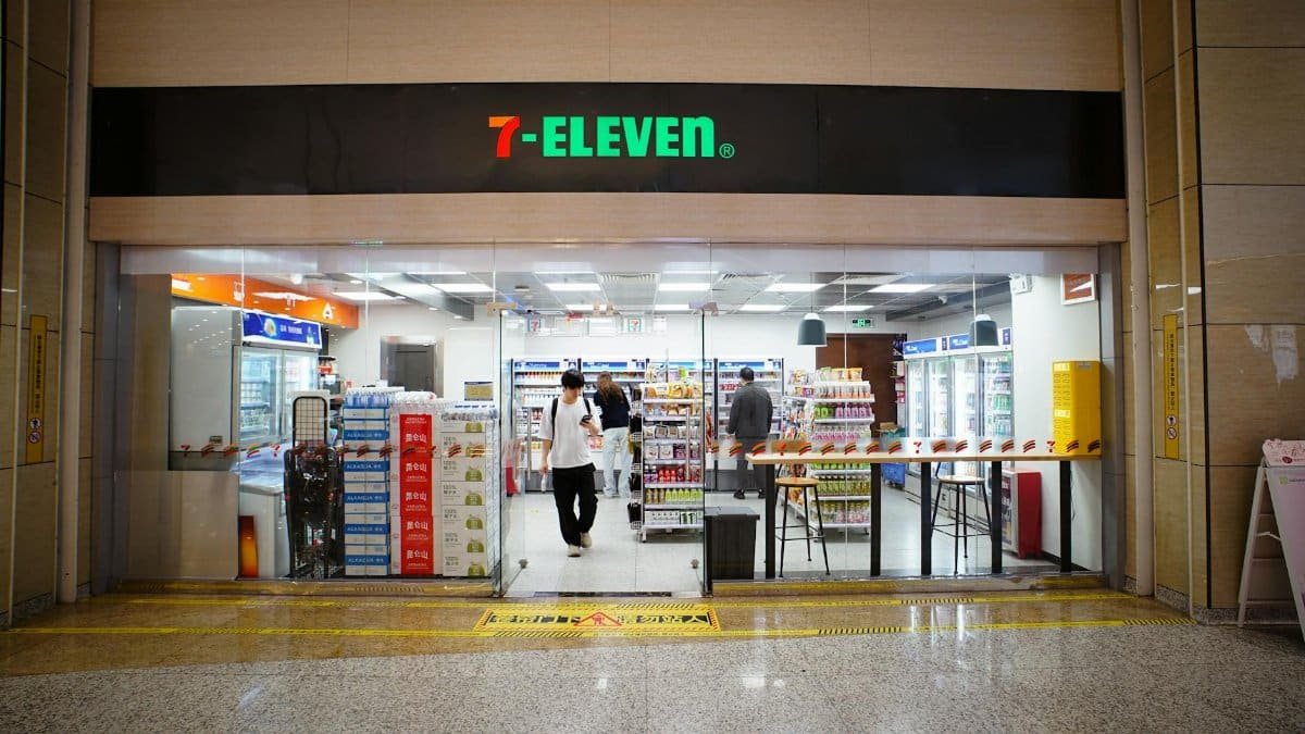 Indoor view of a 7-Eleven store entrance with people shopping and products displayed.