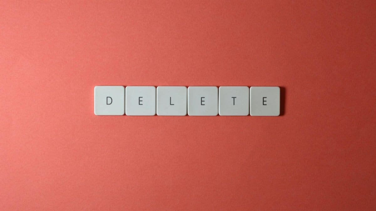 Close-up of keyboard letters spelling 'DELETE' on a coral background, emphasizing digital concepts.