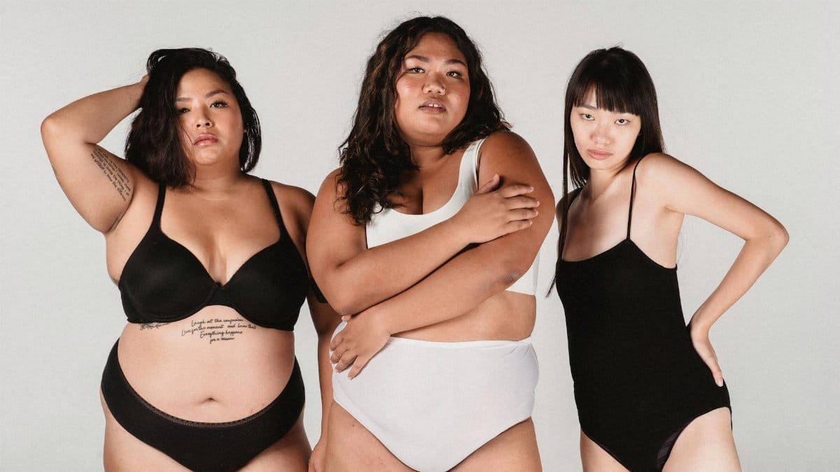 Group of Asian plus size and slender women in underwear looking at camera on white background