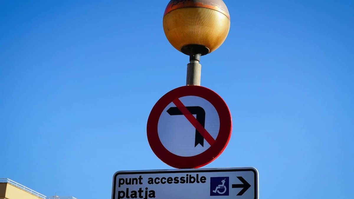 No left turn sign with accessible beach direction in Cala Millor, Spain.