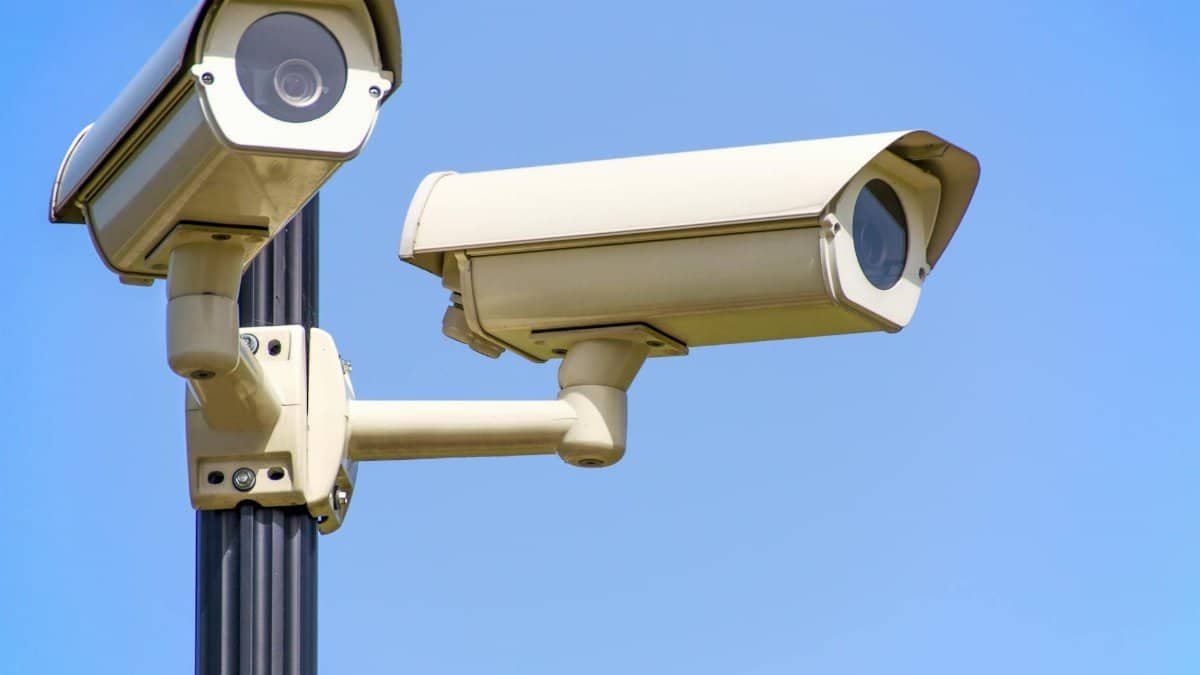 Outdoor security cameras mounted on a pole against a clear blue sky, ensuring vigilant surveillance.