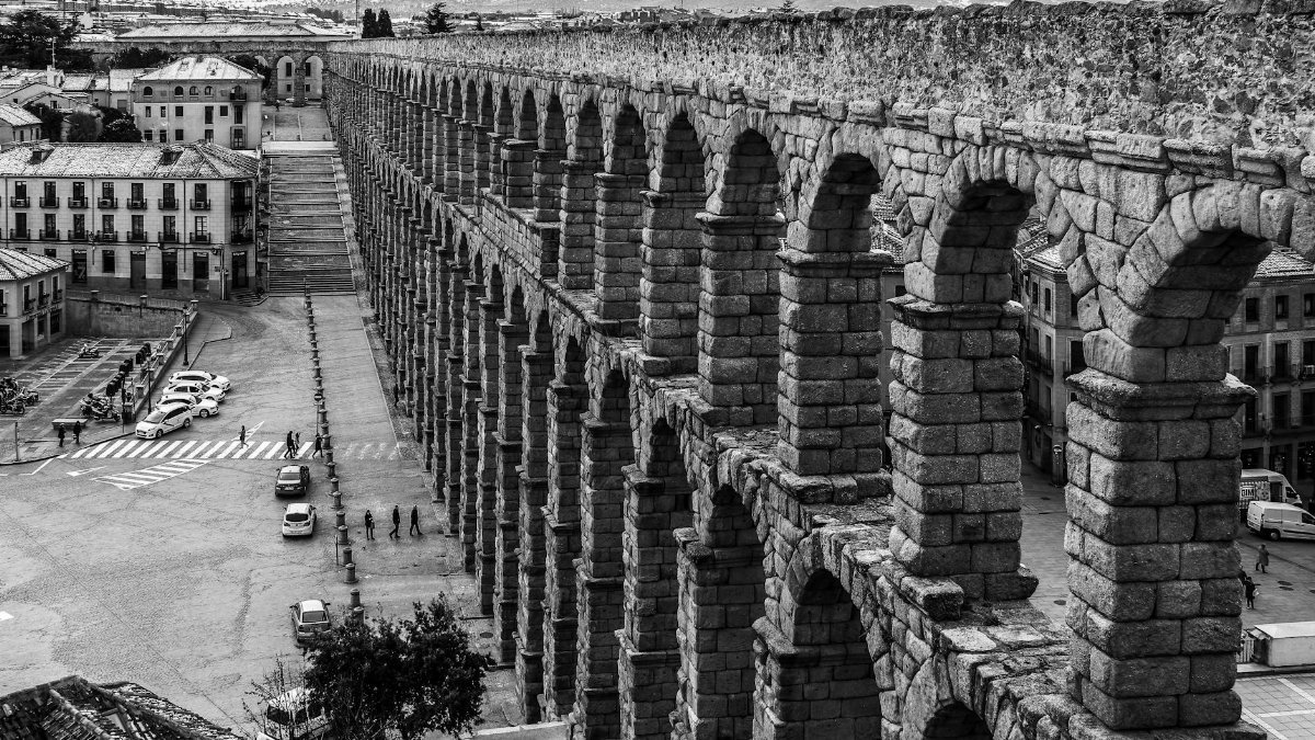 Black and white photo of the historic Segovia Aqueduct in Spain's scenic city center.