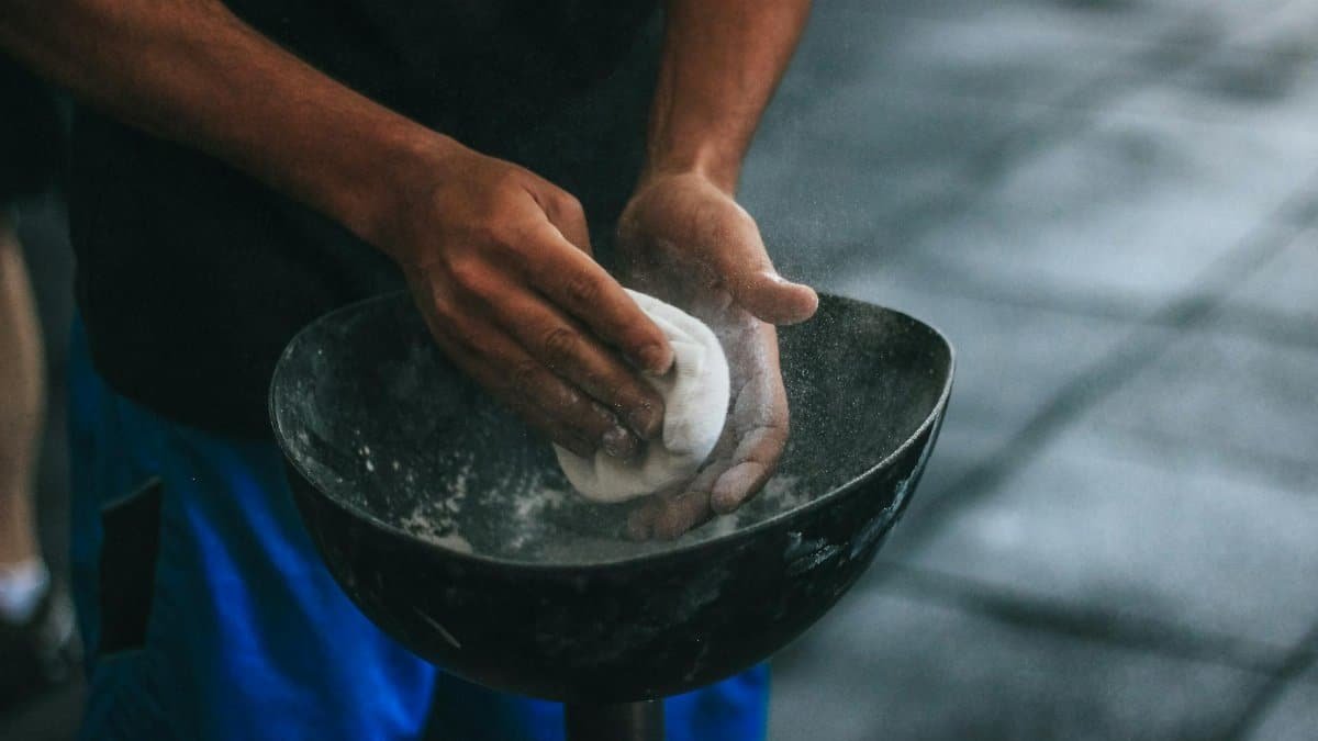 A man prepares chalk powder for climbing exercises with focus on hands in motion.