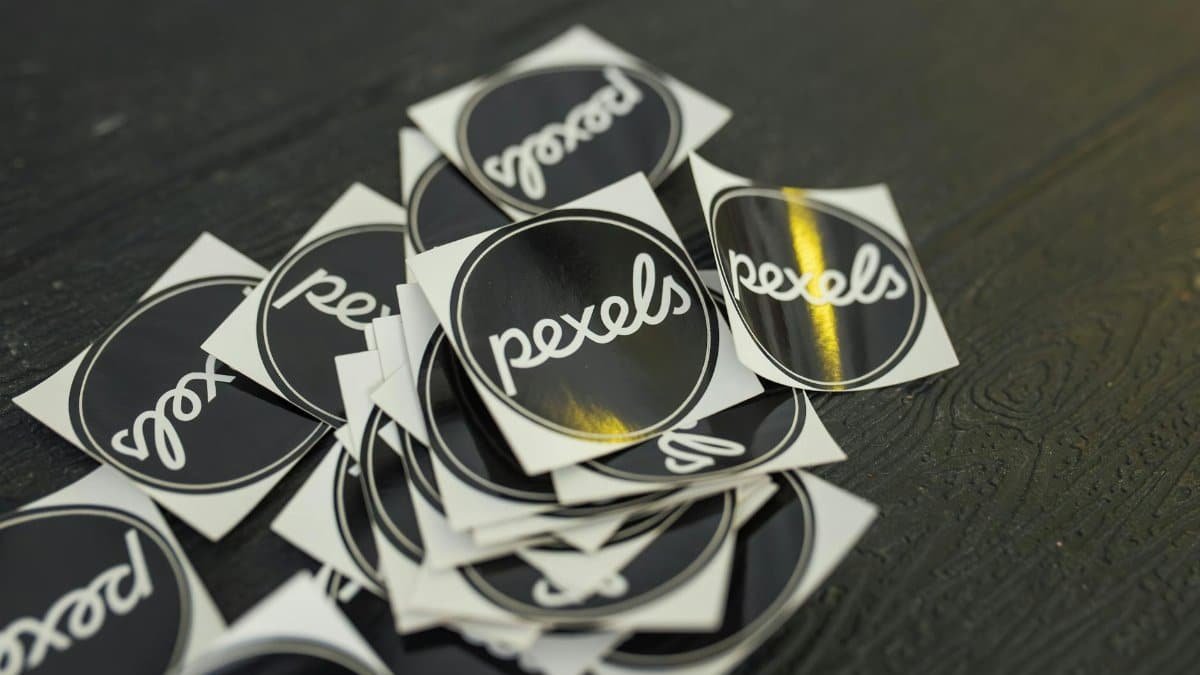 A collection of Pexels branded stickers scattered on a dark wooden surface.
