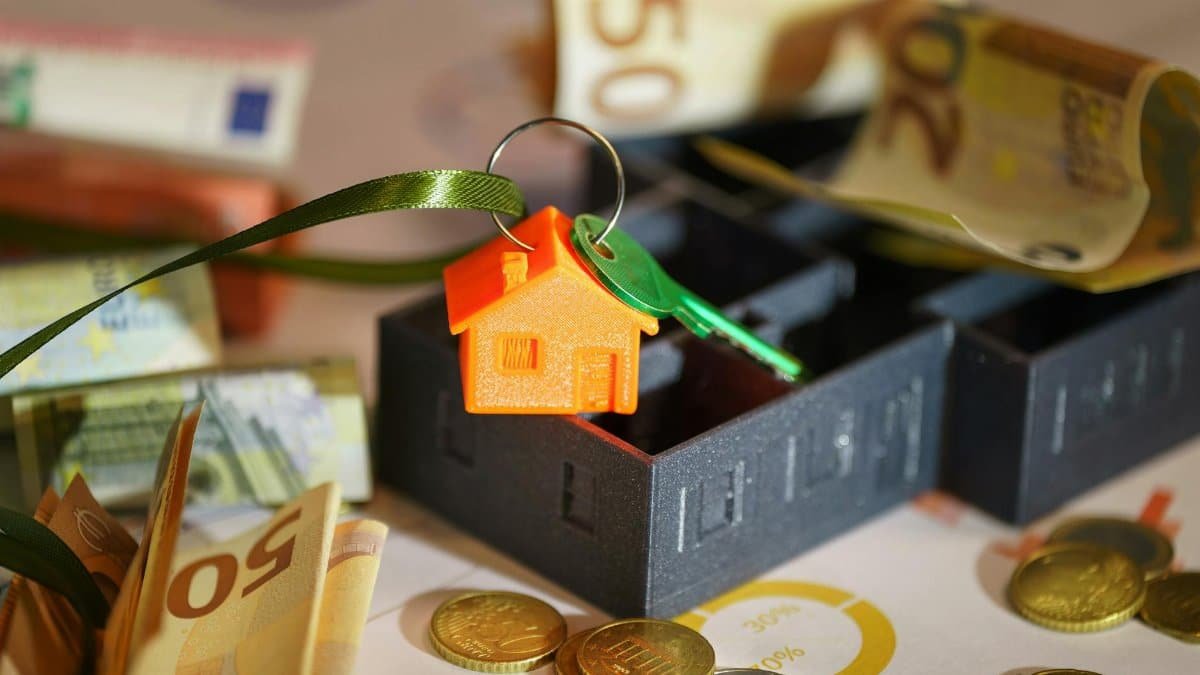 Image depicting real estate investment with keychain, euros, and financial charts.
