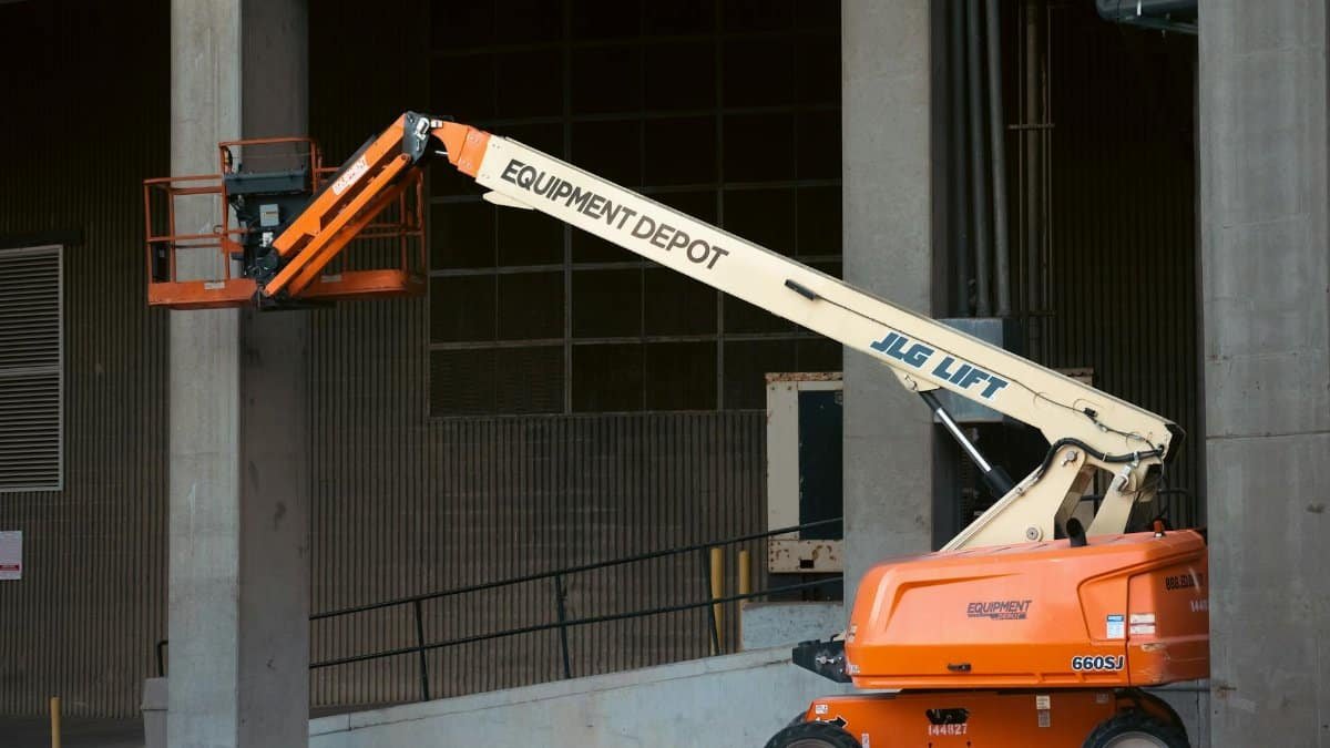 Orange JLG lift positioned at an industrial construction site, ready for use.
