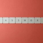 Focus on password security with white keyboard tiles spelling 'PASSWORD' on a coral background.