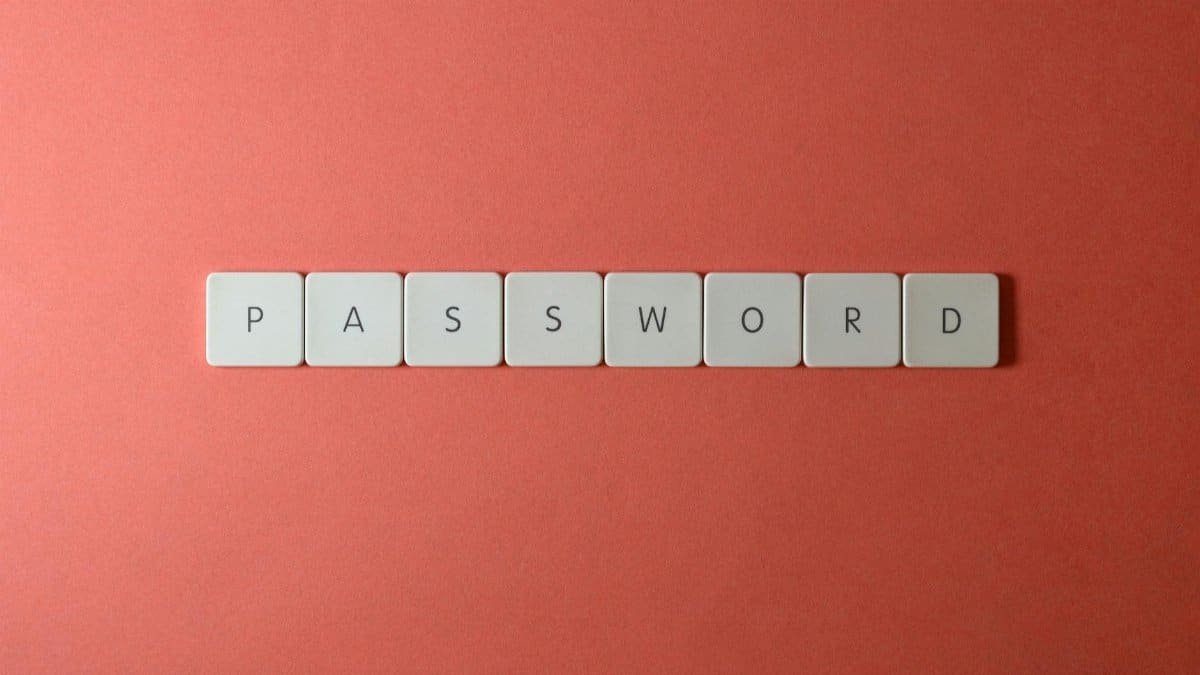 Focus on password security with white keyboard tiles spelling 'PASSWORD' on a coral background.