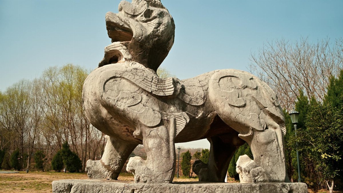 Majestic stone guardian lion sculpture in a park setting, Nanjing, China.