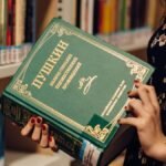 A woman holds a Russian literature book in a library, showcasing a focused study environment.