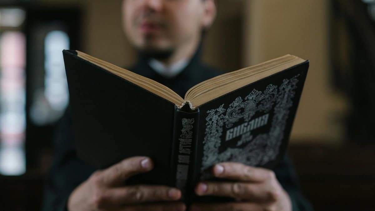 A man reads a Bible inside a church setting, highlighting faith and spirituality.