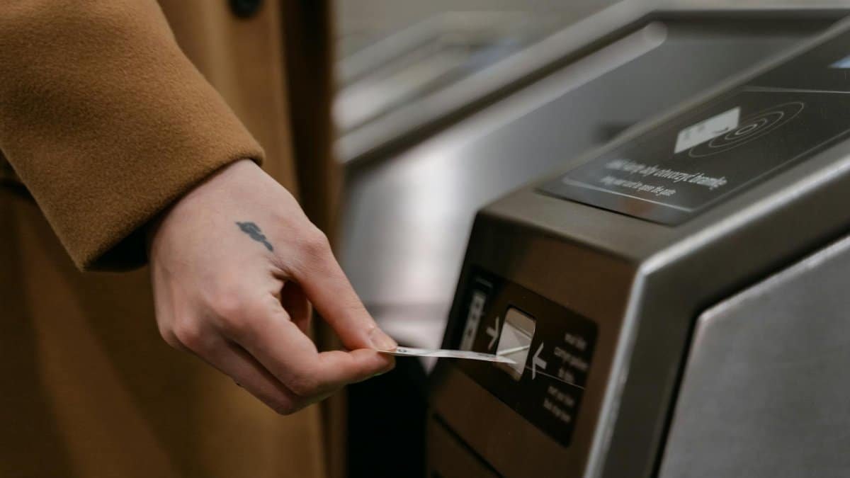 A person inserting a ticket into a turnstile at a train station, showcasing public transportation usage.