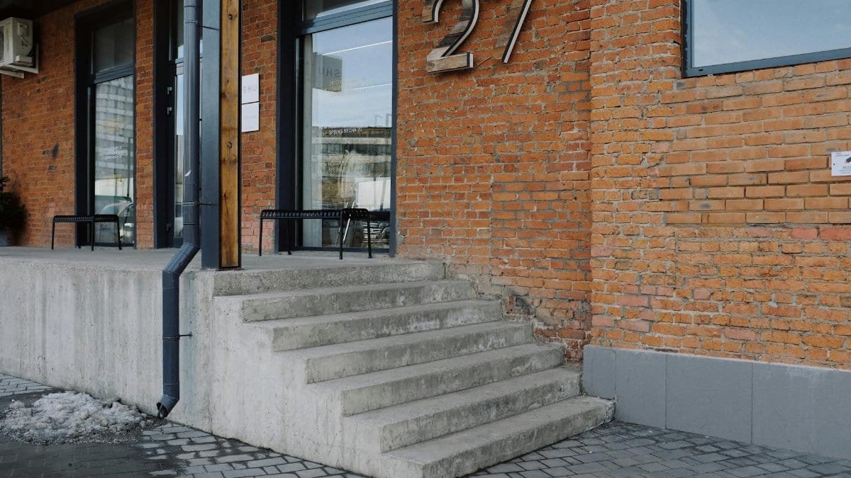 Exterior view of a brick building with concrete stairs, number 27 on the wall.