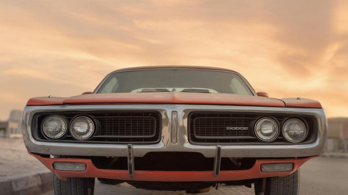Front view of a classic Dodge muscle car under a vibrant sunset in Sharjah, UAE.