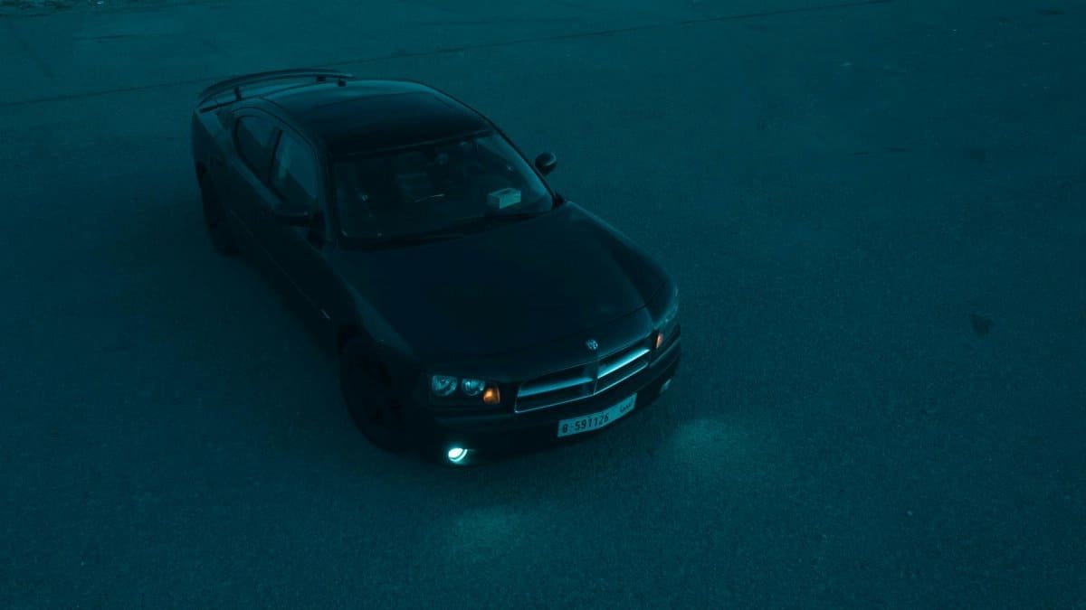High-angle aerial shot of a black Dodge Charger parked at night in Dodge City, Kansas.