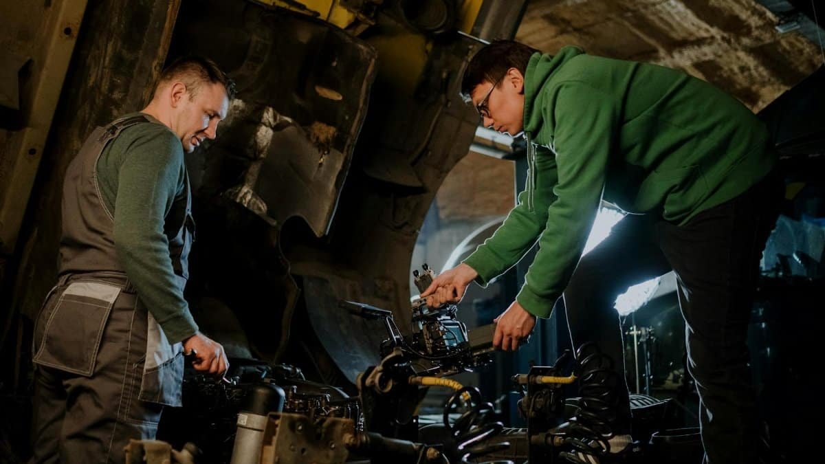 Two mechanics engaged in repairing an engine, showcasing teamwork in an industrial setting.