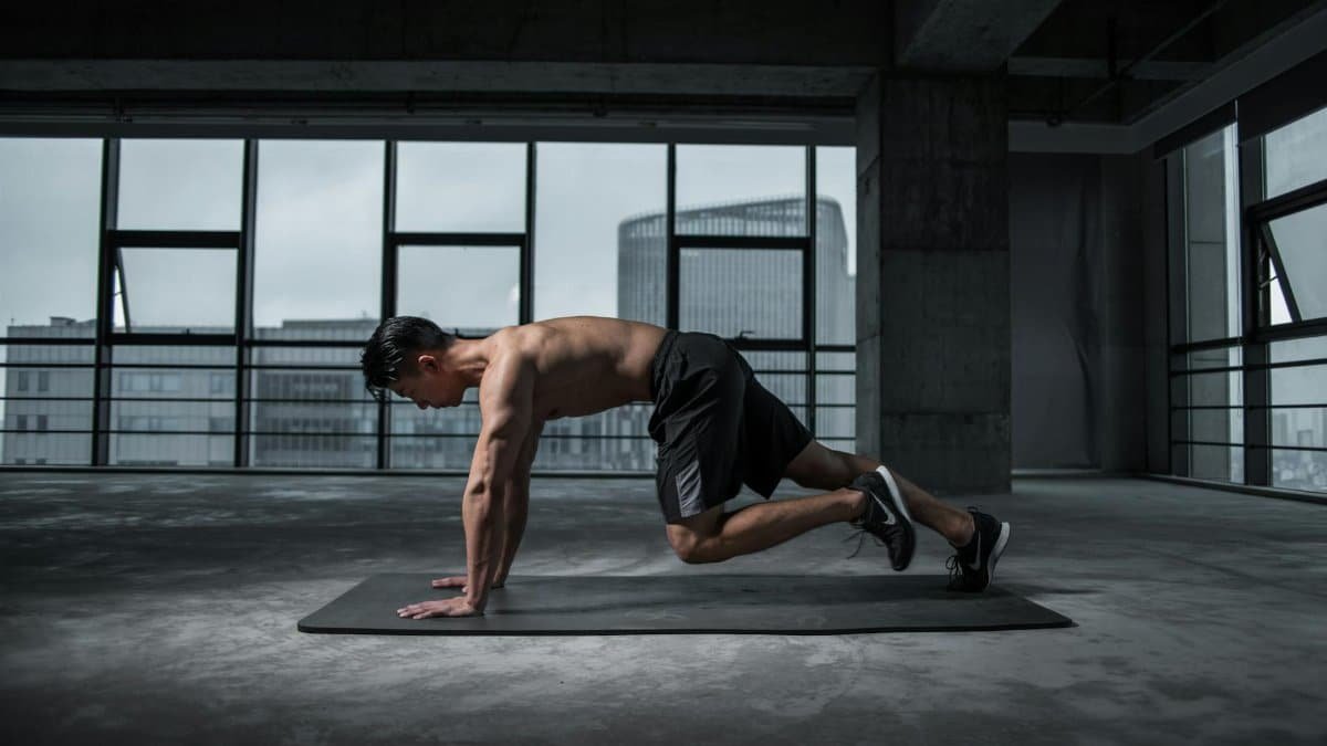Fit man doing mountain climbers exercise inside a modern gym