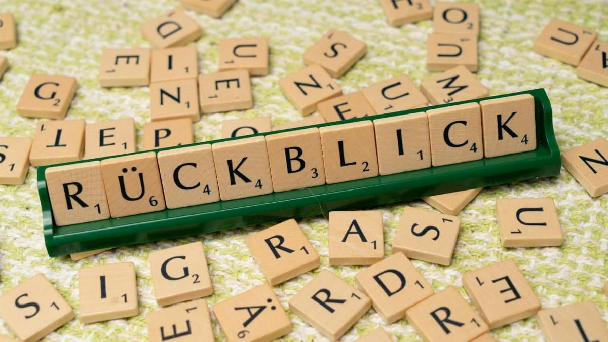 Scrabble tiles spelling 'Rückblick' on a green textured surface, emphasizing language and nostalgia.