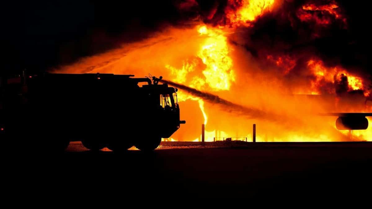 Dramatic image of a fire truck silhouette against a massive blaze, showcasing emergency response.