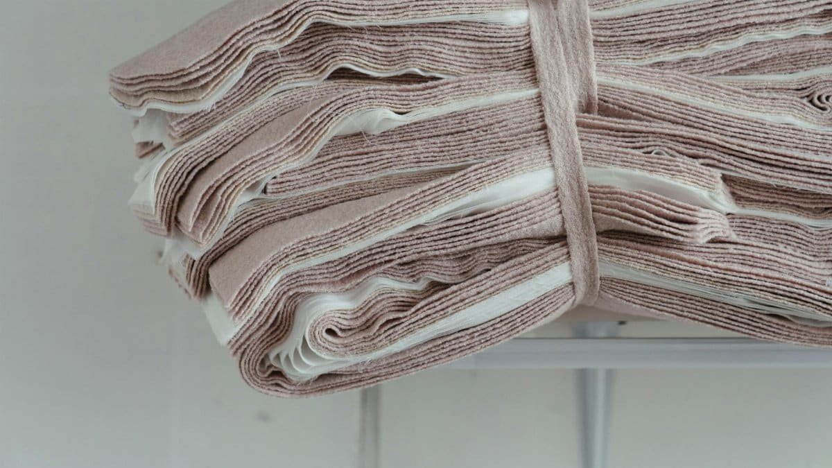 Close-up of neatly stacked pink and white fabric in a sewing workshop, ideal for fashion designs.