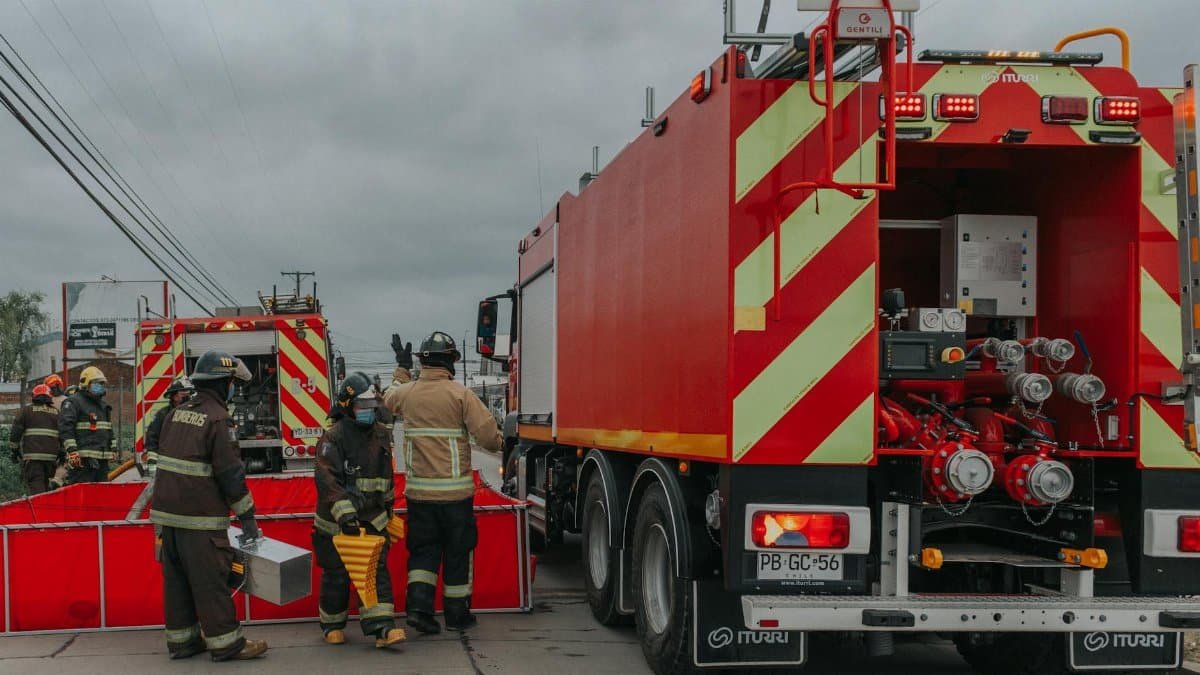 Firefighters preparing equipment with fire trucks during an emergency response effort.