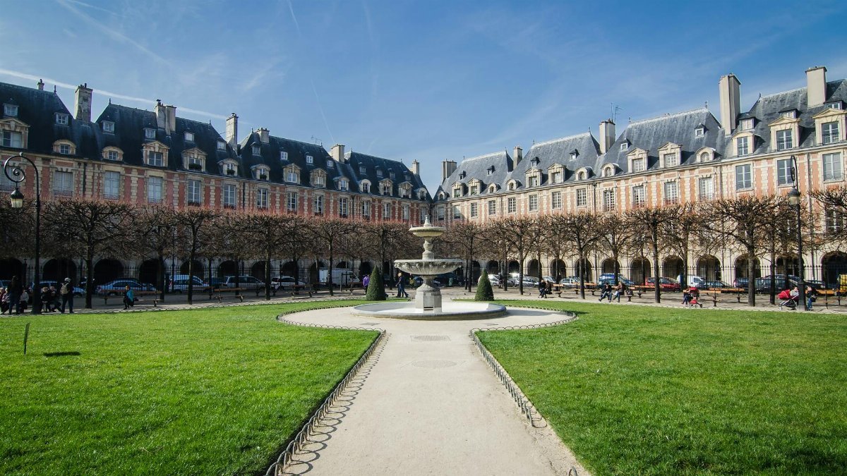 Beautiful day at Place des Vosges with fountain and historic architecture.