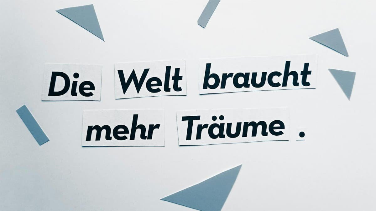 Text cutouts with the German phrase 'Die Welt braucht mehr Träume' on a white background.