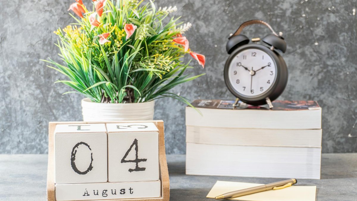 A styled indoor setup featuring a calendar showing August 4 and an alarm clock on books.