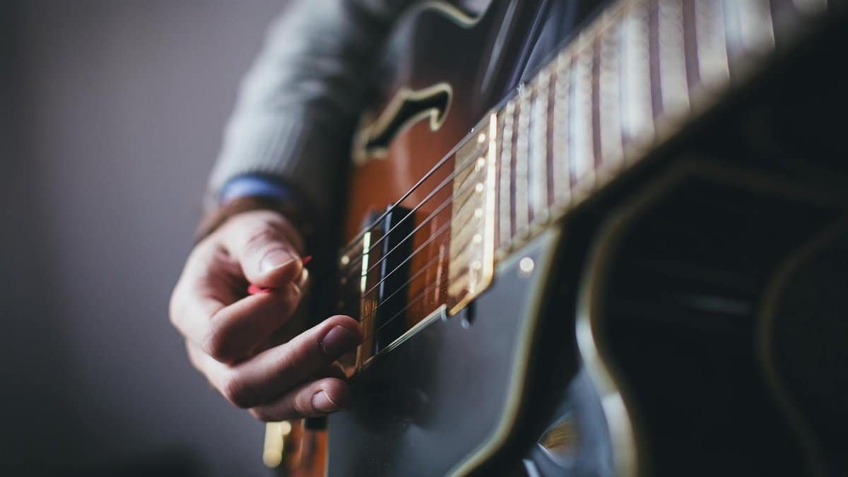 A detailed shot of a musician's hand strumming an electric guitar.