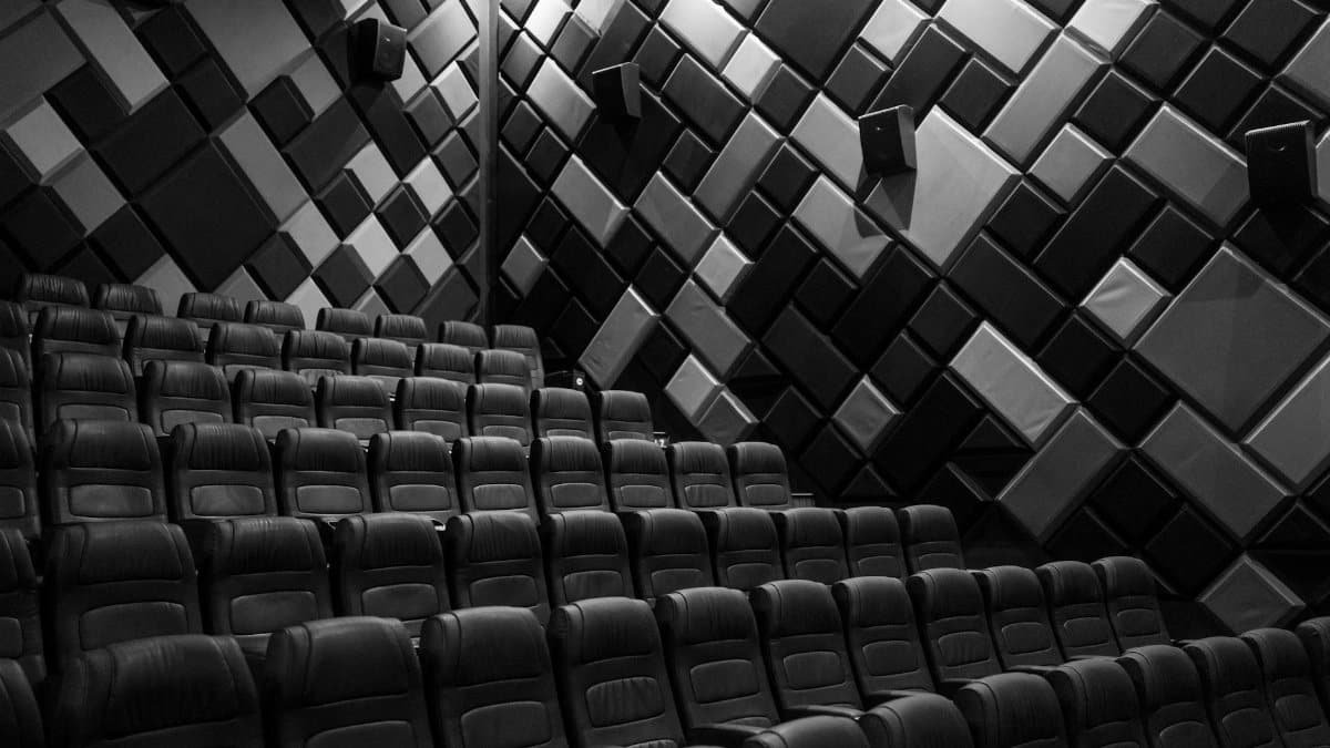 Interior of an empty cinema hall with leather seats and acoustic walls in grayscale.