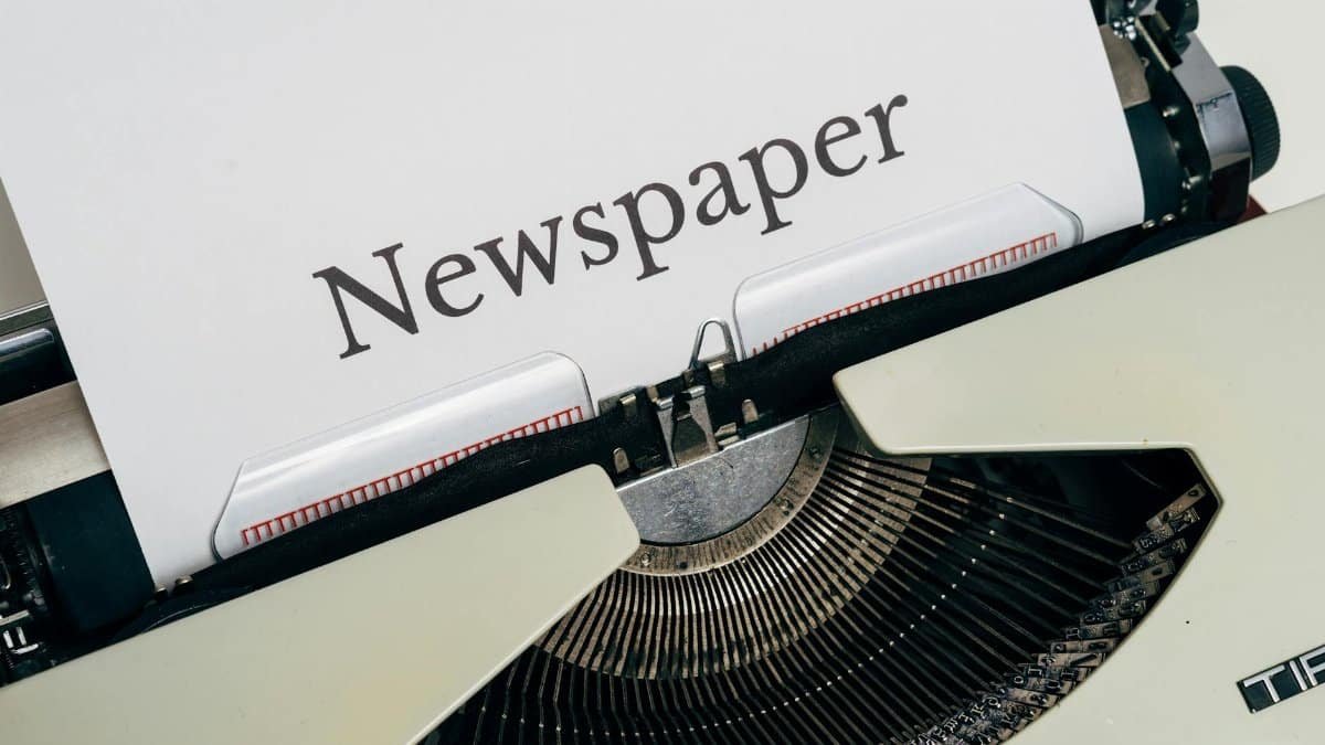 Close-up of a vintage typewriter printing the word 'Newspaper' on paper.