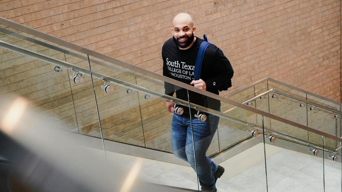 A student confidently ascends steps inside South Texas College of Law building.
