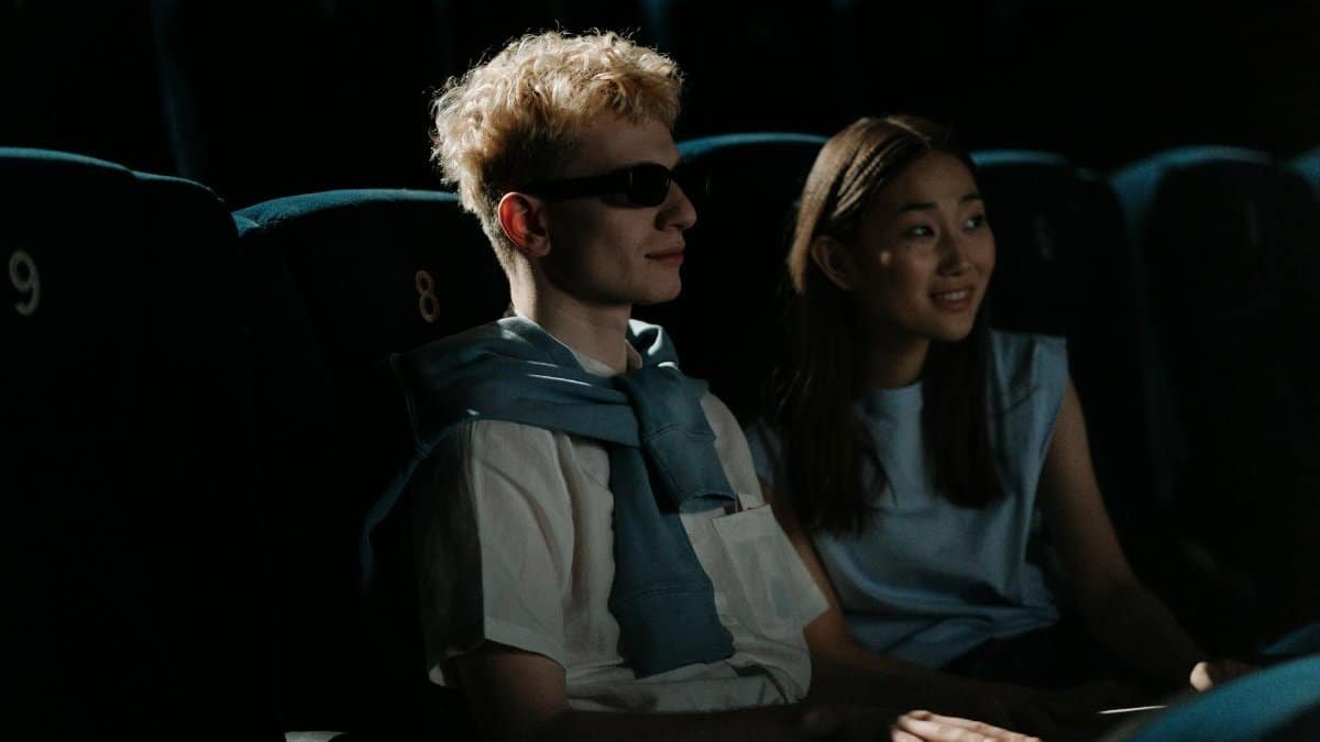 A couple watches a movie in a dark cinema, creating an intimate atmosphere.