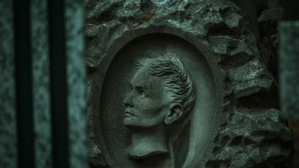 A carved stone relief of a human face captured in dim lighting, adds depth to its ancient, rustic feel.