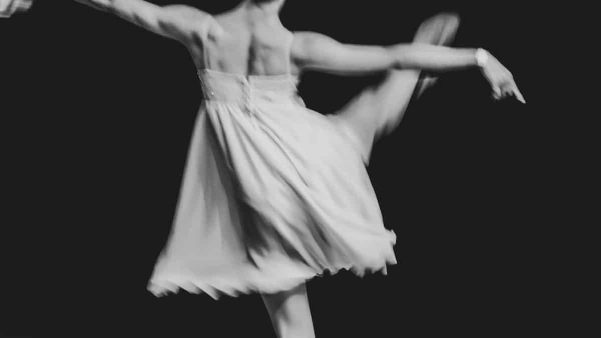 Black and white photo of a ballet dancer captured in graceful motion with blurred effect.