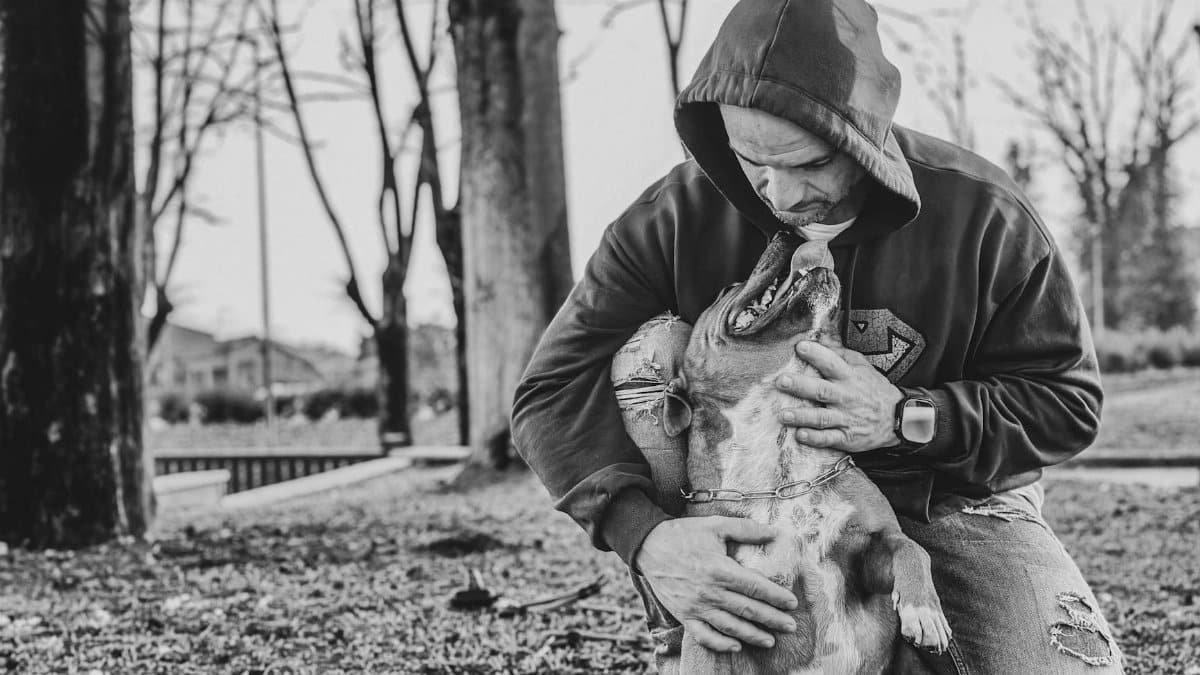 A heartfelt bond between a man and his dog in an outdoor setting. Black and white.