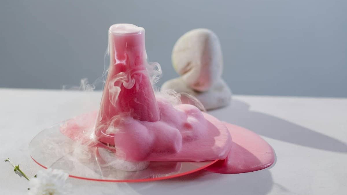 Vibrant pink foam overflowing from a flask in a clean, modern laboratory setting.