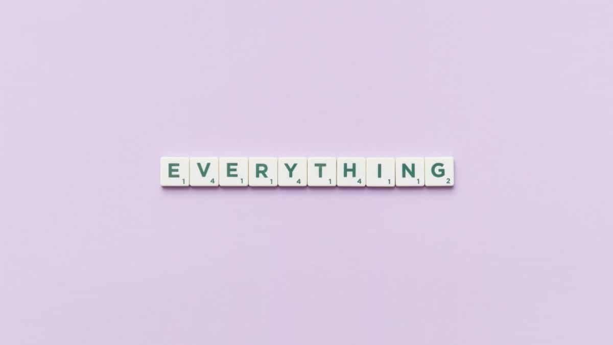 Scrabble tiles spelling 'everything' on a pastel lilac background, showcasing simplicity and minimalism.