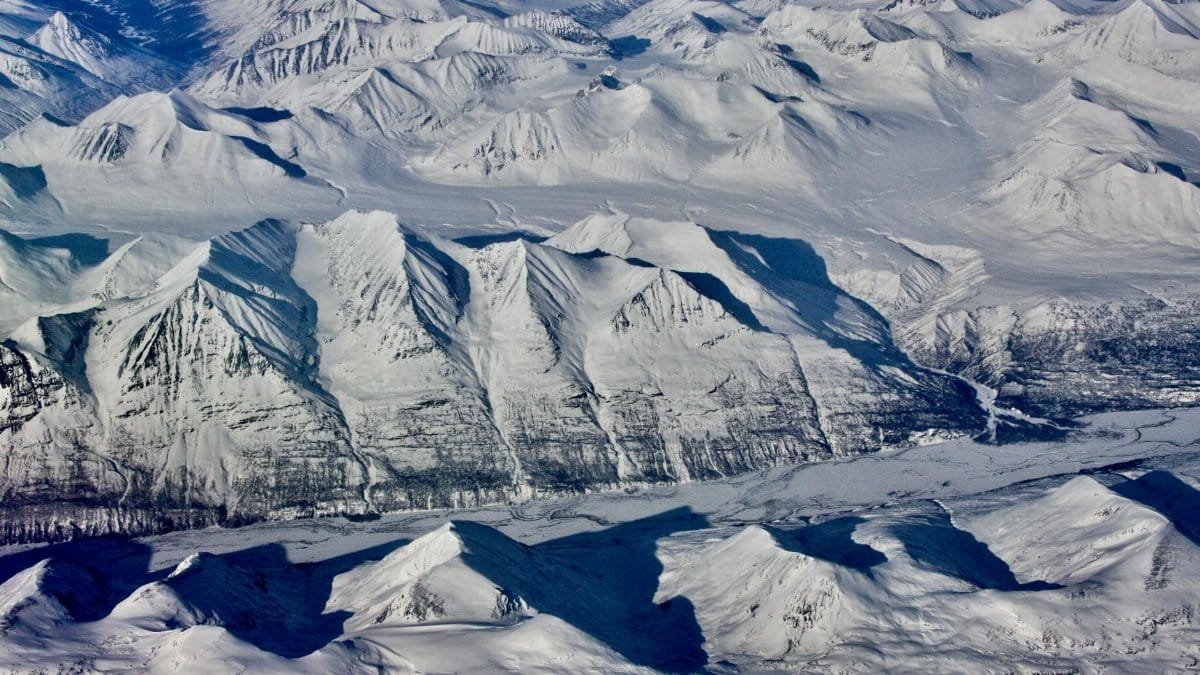 Stunning aerial shot of snow-capped mountains in Alaska, showcasing pristine winter landscapes.