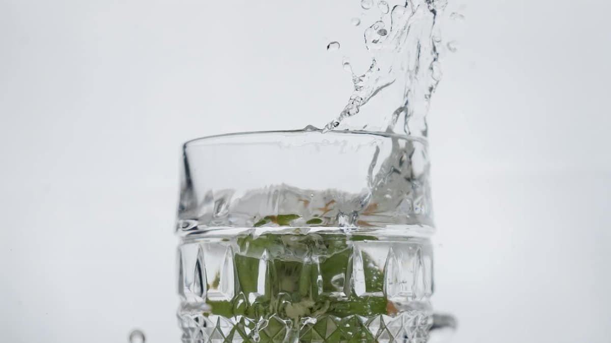 Refreshing water splash in a crystal glass with mint leaves.