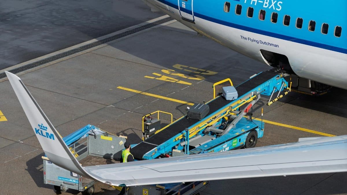 A KLM aircraft being loaded with baggage at an airport, captured on the tarmac.