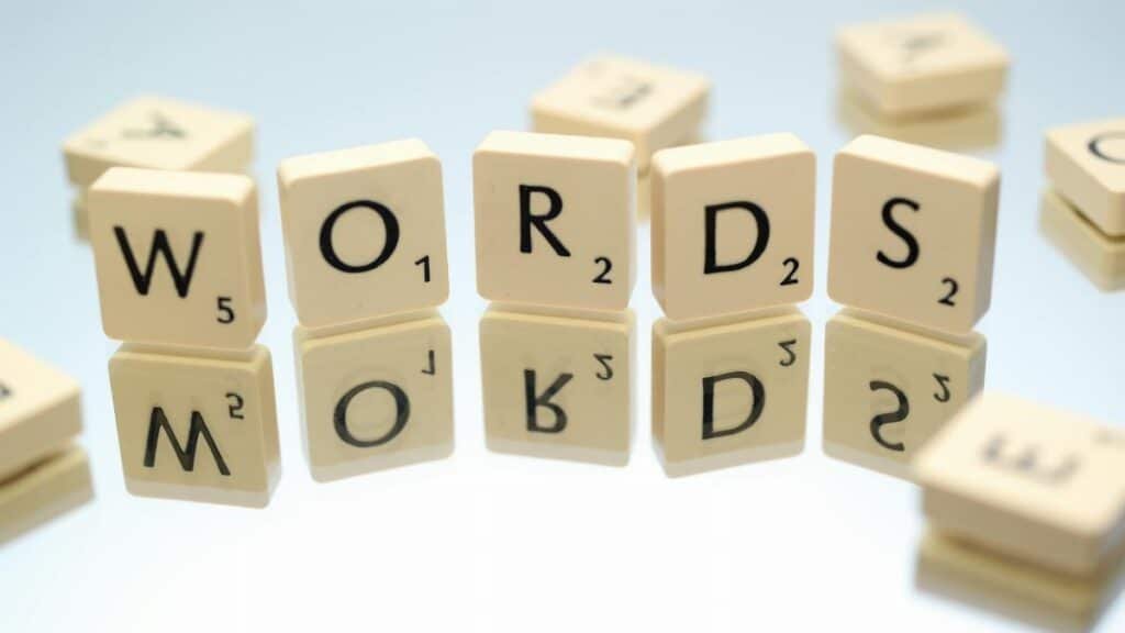 Scrabble tiles spelling 'words' on glass reflecting surface, perfect for language and games themes.