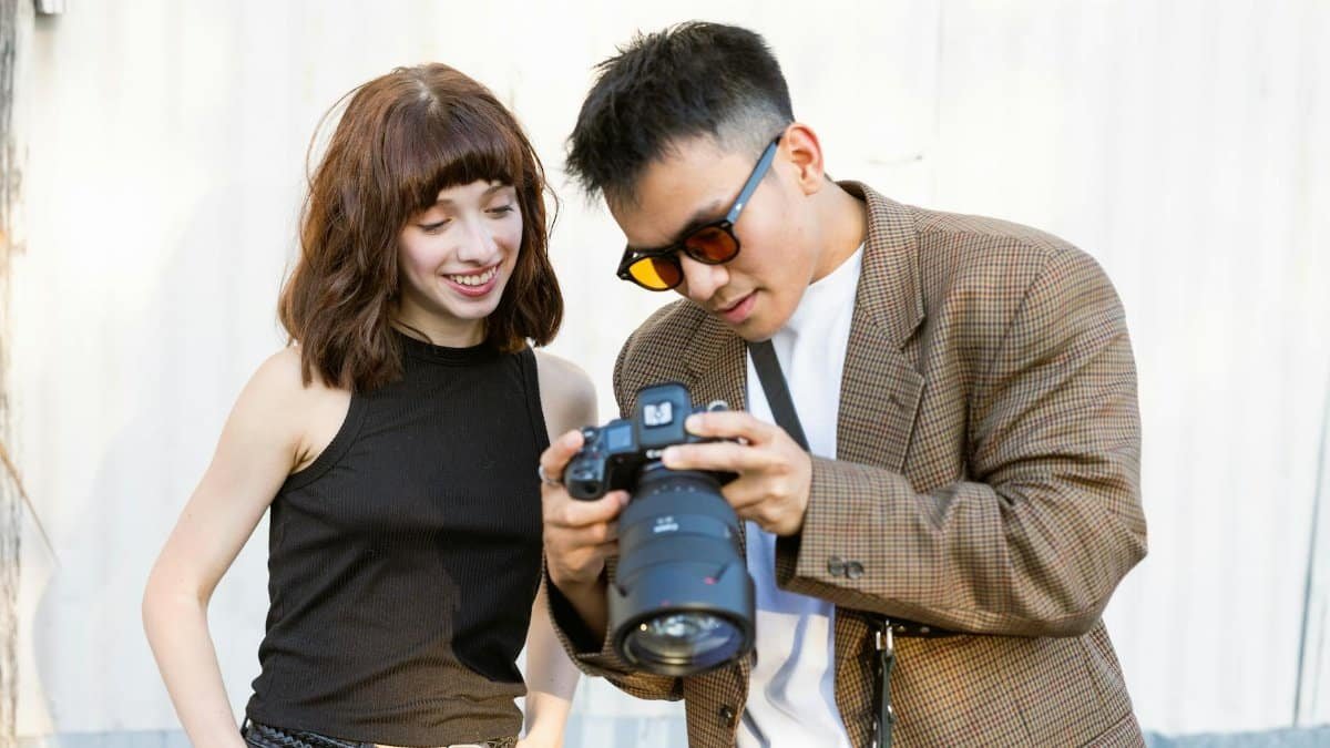 Photographer shows the captured image to a smiling model outdoors.