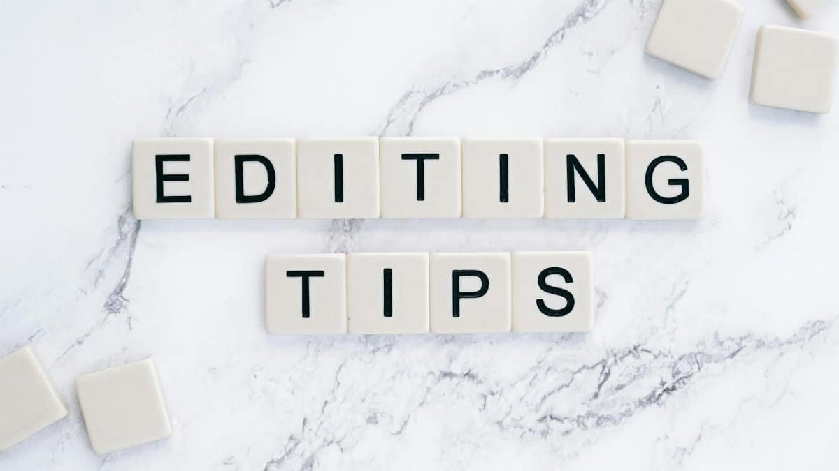 Scrabble tiles spell out 'Editing Tips' on a marble background, perfect for editorial guides.